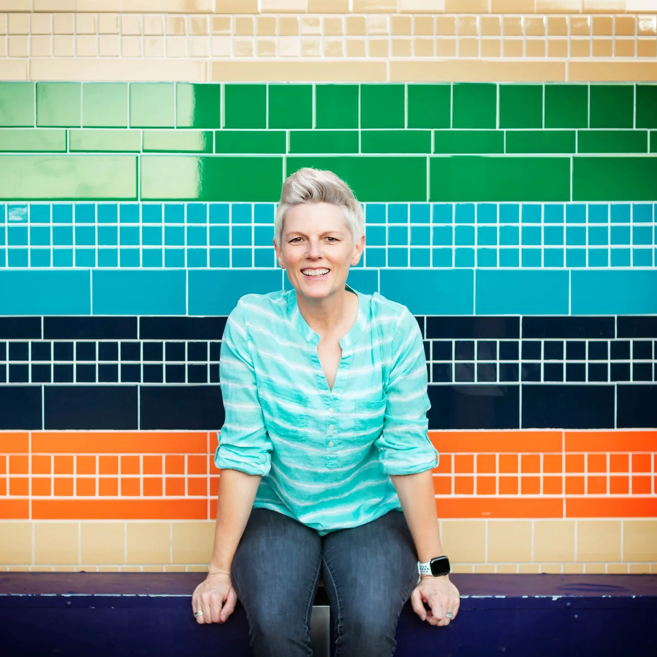 Debbie smiling in front of a bright, colorful tile wall